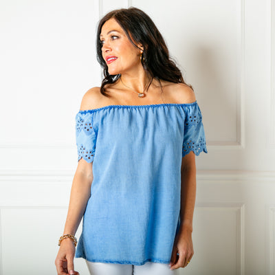 The denim blue Linen Blend Flutter Top with short sleeves that feature beautiful broderie detailaing and can be worn on or off the shoulder